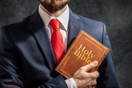 Man looks like politician or businessman stands with holy bible