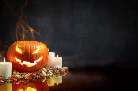 Composition of pumpkin and candles on black background with glowing smoke. Copyspace for your textの写真素材