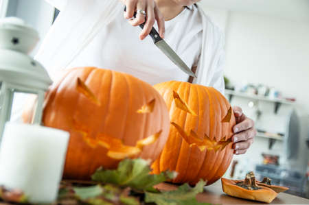 Woman's hand with knife cuts pumpkin for Halloween. Horizontal orientationの写真素材