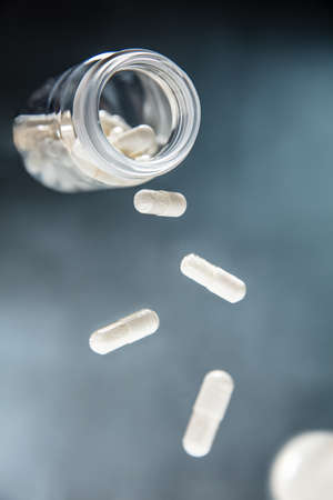 Pills and plastic jar float in the air. Vertical viewの写真素材