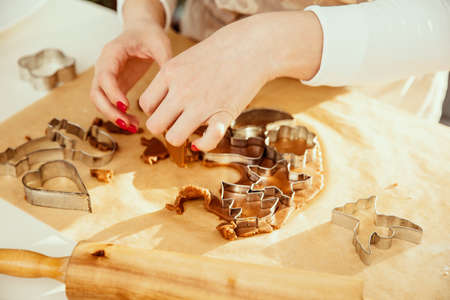 Woman's hand cuts off Christmas dough from gingerbread.