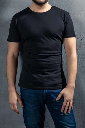 Young healthy man with black T-shirt on concrete background. Picture without model face.の写真素材