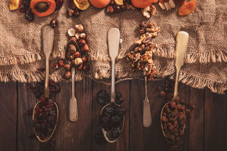 Dried fruits and nuts arranged on a spoon, fabric and an old table. Horizontal composition in the old style.の写真素材