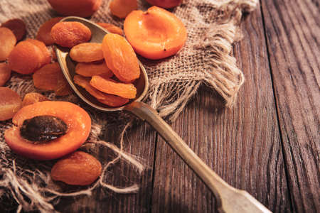 Dried apricots arranged on a fabric and spoon. Composition in the old styleの写真素材
