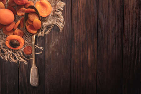 Dried apricots arranged on a fabric and spoon. Composition in the old style with a view from the top and copy space for your textの写真素材