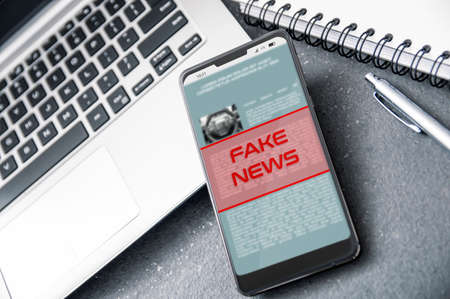 Laptop and smartphone with "fake news" alert on the screen. Conception of increasing level of fake news.の写真素材