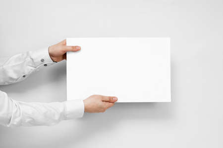 Hands hold from the left white board with copy space on white background.