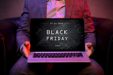 Black friday banner on the display of a modern laptop that is holds by an elegant man.の写真素材