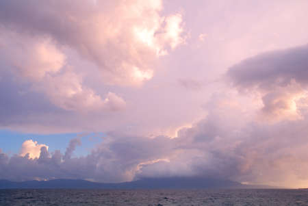Colorful heavy clouds above land and sea water