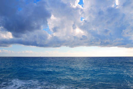 Heavy clouds and vast deep blue sea watersの写真素材