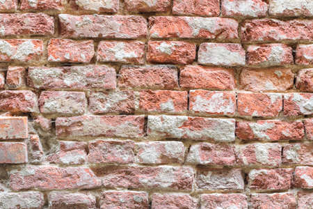 Old damaged red brick wall with battered plasterの写真素材