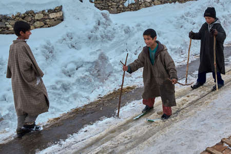 Azad, Kashmir, India - February 16 2012 : Ð¡children descend from the mountain on skis made of tin pipes.のeditorial素材