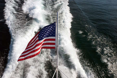 Waving in the wind US flag on the background of the ship wakeの写真素材