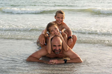 Dad, son and daughter fooling around in the water on the beach in the area Indian Shores, Florida, USAの写真素材
