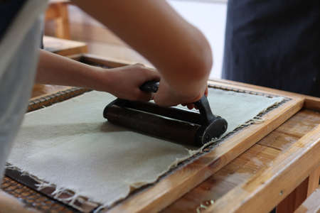 Production of paper from elephant dung. Hand squeezed water. A thin layer of paper is between the two canvases.の写真素材