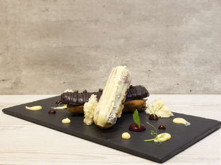 Dessert served on slate. The dessert is decorated with cherry cream, white chocolate and mint.