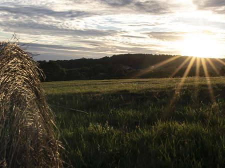 Summer sunset from the meadow with hay bales.の写真素材