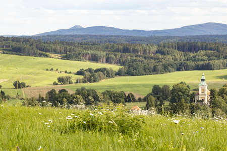 View of the church and a small village in a romantic valley surrounded by meadows and pastures.の写真素材