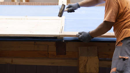 The worker hammeres a nail into the batten during the reconstruction of the roof.の写真素材