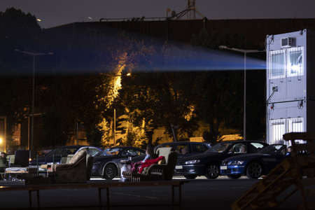 People are watching a movie in a car cinema in the moonlight.のeditorial素材