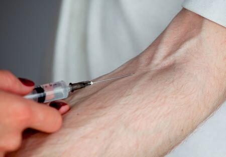 Intravenous injection by medical doctor to young girl separately on the grey background
