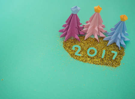 Colorful origami paper to make Christmas tree,  decorated on green background for creative Merry...