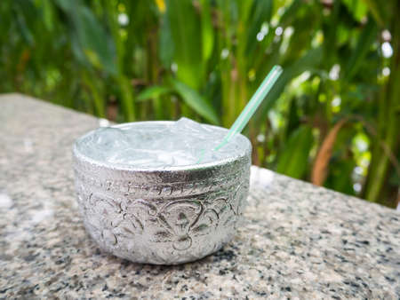 Aluminum bowl with water and  ice cube on the dining table in the restaurant, Thai styleの写真素材