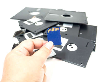 hand holding new memory card in front of group of old memory storageの写真素材