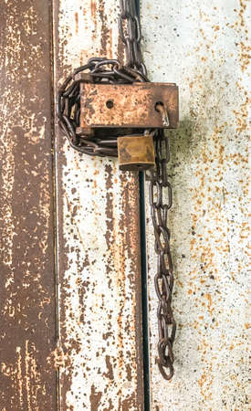 Old padlock and chain locking door are rusty  and insecure, safety conceptの写真素材