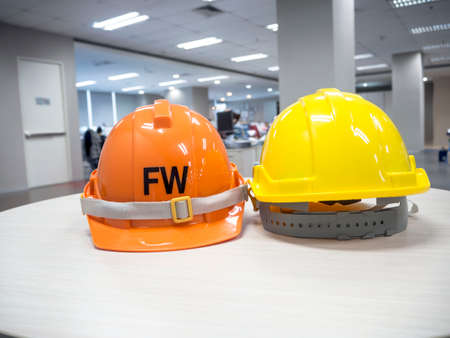 The yellow and orange safety helmet on the table concept security and protectionの写真素材