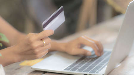 girl hand holding credit card mock up and using  to checking internet online bill on computer, bank...