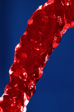 Flowing juice stream over blue backgroundの写真素材