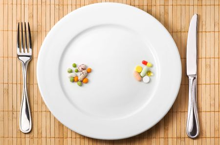 Drugs and beans on the plate illustrating choice between trditional and complementary medicineの写真素材