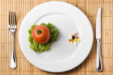 Drugs on the plate illustrating choice between medicine and healthy eatingの写真素材