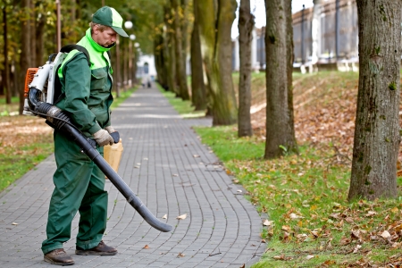 Landscaper operating gasoline Leaf Blower while cleaning the tracks in the park