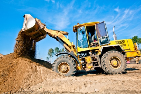 Wheel loader machine unloading soil during earthmoving works at construction siteの写真素材