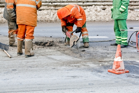 Cutting road works with hydraulic driven angle grinder, upgrading road surfaces; horizontal orientationの写真素材