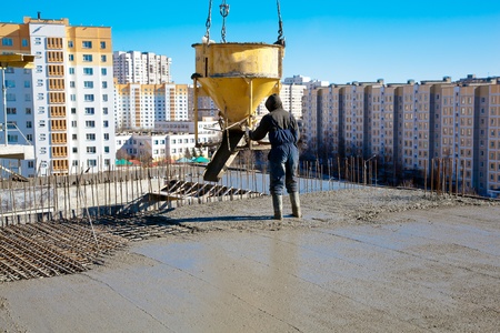 Construction worker pouring concrete during commercial concreting floors and building reinforced concrete structuresの写真素材