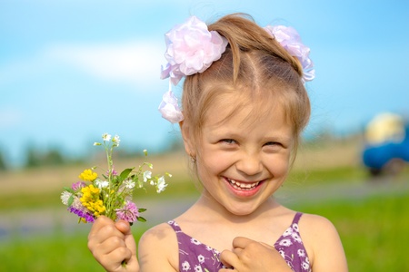 Happy smiling girl with flowers having fun outdoorsの写真素材