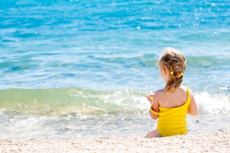 Small girl sitting back on the shore of the seaの写真素材