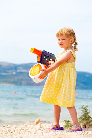Caucasian girl playing with water gun at the seashoreの写真素材