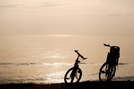 Silhouettes of two bikes on the coast during sunsetの写真素材