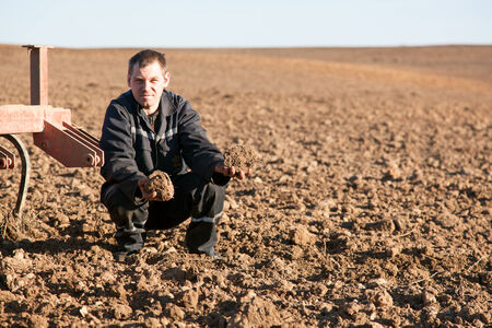 Farmer man in cultivated field holding soil in palmsの写真素材