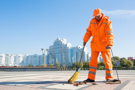 Man street sweeper cleaning city sidewalk with broom tool and dustpanの写真素材