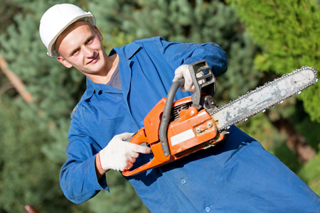 Smiling lumberjack Worker with Chainsaw in Work Wear on Forest backgroundの写真素材