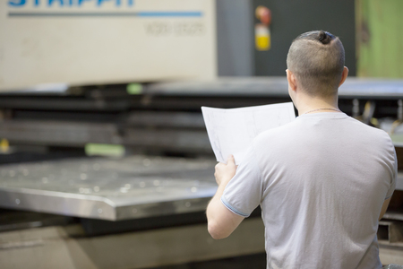 Man worker look engineering drawing blueprints on cncの写真素材