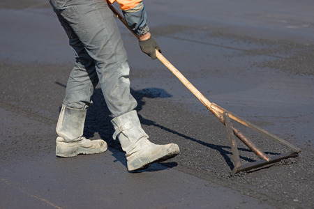 Construction road worker levelling hot mix flexible asphalt concrete pavementの写真素材