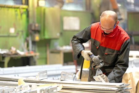 Metalworking industry: factory worker using angle grinder in manufacture workshopの写真素材
