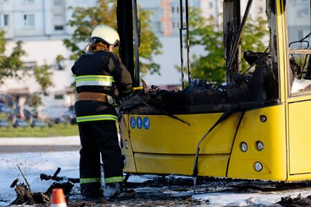 Cal Fire firefighter using axe while extinguish fire that had engulfed entire public transit busの写真素材