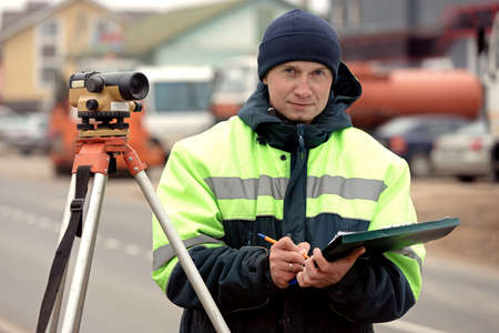 Construction works with tacheometer theodolite. Professional engineer surveyor during road worksの写真素材